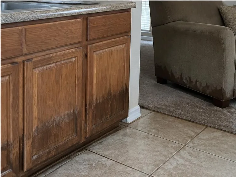 Wet lower kitchen cabinets beside a soaked upholstered chair.